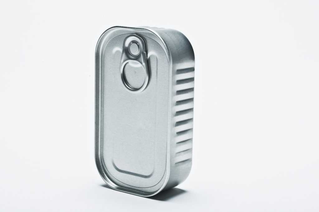 Empty sardine or spam can standing upright against white background
