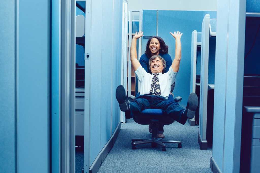 woman pushing man in office chair party silly bad behavior